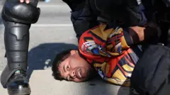 Demonstrant leži na zemlji, okružen policajcima 