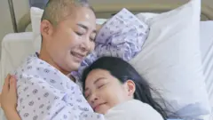 ရောဂါကြောင့် ဆံပင်ဆုံးရှံးသွားတဲ့မိခင်က ဆေးရုံကုတင်ပေါ်မှာ သမီးဖြစ်သူကို ပွေ့ဖက်ထားပုံ (သရုပ်ဆောင်ရိုက်ကူးမှု)