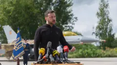 Ukraine President Voldymyr Zelensky make speech in front of one of di F-16 fighter jets wey Ukraine receive in July