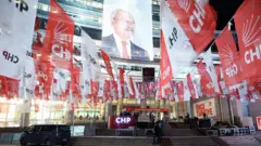 CHP flmalarıyla süslü bir sokak sonunda merdivenler ve Kemal Kılıçdaroğlu posterinin asılı olduğu bir bina görünüyor. Gece ve binada aydınlatma mevcut. 