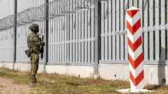 Солдат польської прикордонної служби стоїть на варті перед прикордонною стіною