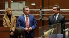 El abogado Alan Jackson habla junto a otras dos personas en la sala del tribunal
