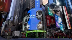 Zdjęcie przedstawiające ruchliwą miejską ulicę z drapaczami chmur oraz niebiesko‑białą reklamę Polymarket pokazującą prognozy dla Zohrana Mamdaniego i Andrew Cuomo oraz sylwetki obu polityków zwrócone ku sobie.