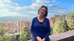 Marcela Pedraza sentada em um terraço. Atrás dela estão vários prédios
