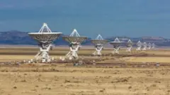Fotografia colorida mostra antenas no chão do deserto apontadas para o céu