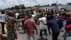 Ọpọlọpọ ero duro ni gbagede kan, wọn n fi ọwọ ti ara wọn, ọpọ wọn lo jẹ ọkunrin, ti wọn si wọ oniruuru asọ sọrun