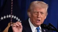 Donald Trump dey tok during one press conference after a US strike on Venezuela where dem capture President Nicolas Maduro. Trump wear navy suit, white shirt and blue tie.