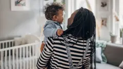 A woman carrying a baby