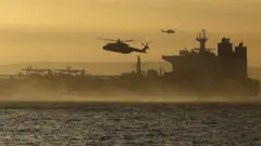 A helicopter in the sky above a seized tanker in the English Channel