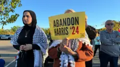 Una mujer musulmana sostiene un cartel que llama a no votar por Kamala Harris, en Dearborn, Michigan.