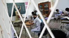 Students wearing facemasks sit in a classroom after their school was reopened in Colombo on July 6, 2020