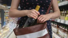 Mulher colocando garrafa em bolsa dentro de loja