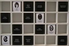 24 Nisan'da tutuklanan aydınların fotoğraf ve isimlerinin yer aldığı panonun fotoğrafı. Aydınların görselleri beyaz kağıt üzerinde, sadece isimlerin yazdığı kağıtlarsa siyah renkli. 