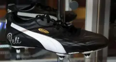 Botín de fútbol negro con sello que dice King en dorado, franja blanca, y la firma de Pelé en el costado.