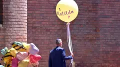 मटिल्डा लेखेको बेलुन उडाउँदै एक पुरुष