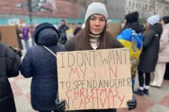 امرأة تحمل لافتة تطالب بإطلاق سراح ابنها