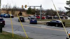 奥に建物があり、手前の道路に複数のパトカーを含む多数の車両が停まっている