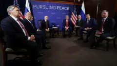 El presidente ruso, Vladimir Putin, y el presidente estadounidense, Donald Trump, asisten a una reunión, mientras el asistente presidencial ruso, Yury Ushakov, el ministro de Asuntos Exteriores ruso, Sergey Lavrov, el secretario de Estado estadounidense, Marco Rubio, y el enviado especial estadounidense, Steve Witkoff, se sientan cerca, en la Base Conjunta Elmendorf-Richardson en Anchorage, Alaska.