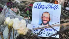 クリーム色やピンク色などの花と、プレティ氏の笑顔の写真が並んでいる