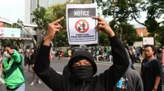 Para pengunjuk rasa menampilkan poster selama protes terhadap Kepresidenan Prabowo pada 29 Agustus 2025 di Surabaya, Indonesia.