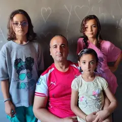 Alathamna con tres de sus hijos, todos miran fijamente a la cámara.