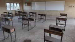 Picture of classroom wey show empty chairs and desks.