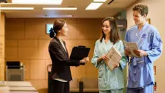 Casal de pacientes conversa com funcionária de uma clínica médica