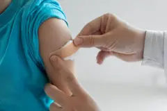 aşı olan bir çocuğa pansuman yapılıyor 