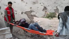 Des sauveteurs transportent un migrant blessé après l'attaque d'un centre de détention, à Saada, au Yémen (28 avril 2025).