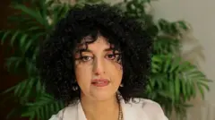 白い服を着たイランの人権活動家モハンマディ氏が、カメラを見つめている