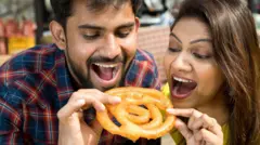 జిలేబీ తింటున్న ఇద్దరు వ్యక్తులు