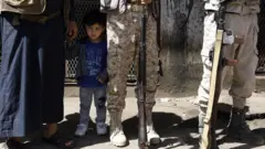 ኣብ መንጐ ዕጡቓት ደው ዝበለ ህጻን