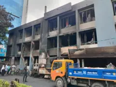 আগুনে ভস্মীভূত মিরপুর থানা। সামনে দুটি পিকআপ ট্রাক ও বাইসাইকেল। কয়েকজন মানুষ দাঁড়িয়ে আছেন