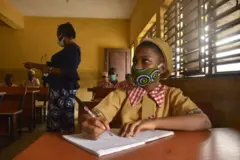 Akẹkọọ obinrin to n kọwe ninu kilaasi pẹlu olukọ rẹ lẹyin rẹ