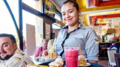 Una camarera en un bar de Valencia, España, sonríe a la cámara.