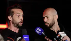 Andrew Tate e seu irmão Tristan (à esquerda) falam com repórteres de TV após retornar de uma viagem aos Estados Unidos, em março de 2025