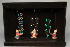 Três palhaços de brinquedo parecem estar fazendo malabarismos com tacos, bolas e aros;.