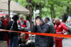 A man holds his head in his hands in front of the school where a 13-year-old shot dead eight classmates and a school guard