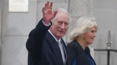 O rei Charles acena enquanto caminha ao lado da rainha Camilla