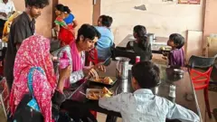 Comensales comiendo en varias mesas en una cafetería de basura.