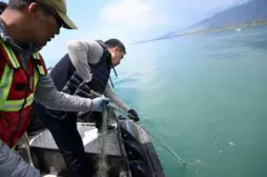 Садыр Жапаровдун Ысык-Көлдү синтетикалык тордон тазалап жаткан сүрөтү. 2023-жыл, июнь