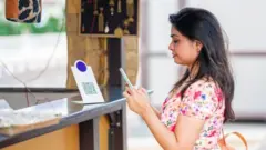 మొబైల్‌తో చెల్లింపులు చేస్తున్న మహిళ