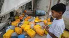 A Palestinian boy inspects the site of an Israeli strike that killed 10 Palestinians, including six children, who were queueing at a water distribution point, in Nuseirat refugee camp, central Gaza (13 July 2025)