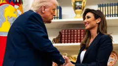 ダークスーツを着たトランプ米大統領と、ニュージャージー州連邦検察トップのハバ氏が向かい合って立ち、握手をしている。ハバ氏は満面の笑顔で、両手でトランプ氏の手を握っている