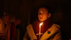 Женщина держит свечку в ходе рождественской службы в Нью-Йорке