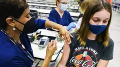A healthworker vaccinates a girl in Florida, August 2021