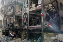 Edificio de varios pisos destruido. En medio de los escombros se ven banderas de Irán