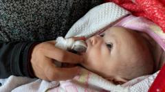 امرأة في غزة تطعم ابنها قطعة تمر بدلاً من الحليب في ظل انقطاعه