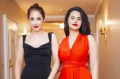 دوه مېرمنې ولاړې دي. د یوې مېرمنې کمیس سور رنګ دی او د بلې تور