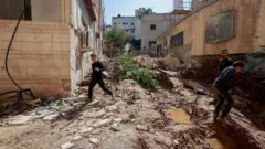 فلسطينيون يتفقدون الدمار الذي أعقب غارة إسرائيلية في يوم سابق في الحي الشرقي لمدينة جنين بالضفة الغربية المحتلة، في 11 مارس/آذار 2025.